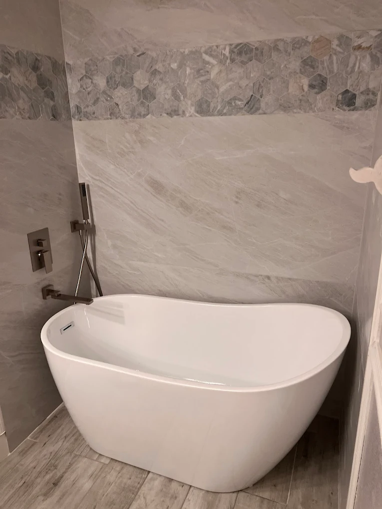 Freestanding soaking tub installation with marble hex tile accent wall