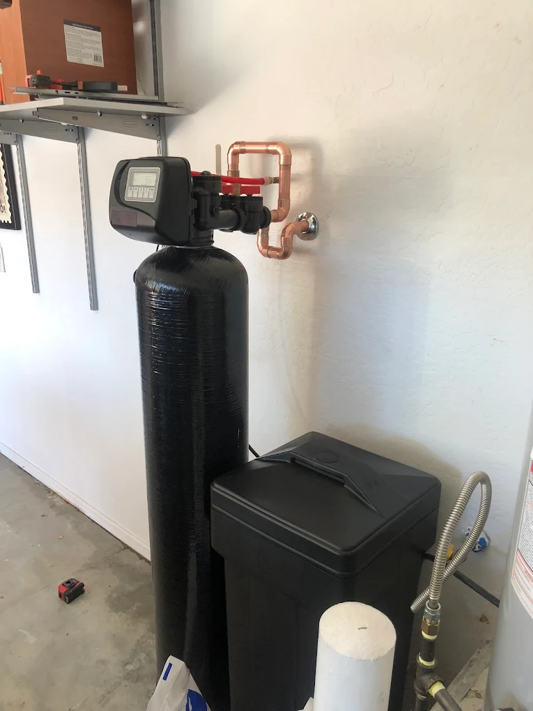 Garage-installed whole-home water softener with copper plumbing and brine tank
